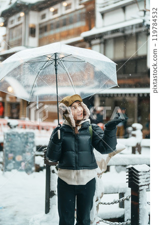 Woman tourist Visiting Ginzan Onsen in Yamagata, happy Traveler sightseeing Japanese Onsen village with Snow in winter season. landmark and popular for attraction in Japan. Travel and Vacation concept 119784532