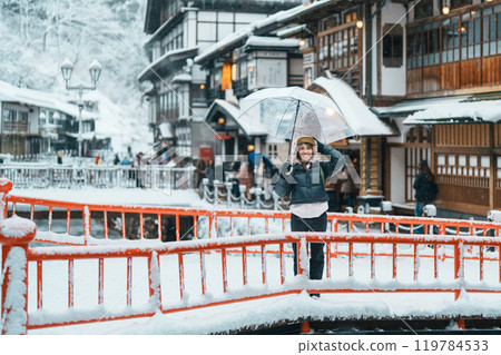 Woman tourist Visiting Ginzan Onsen in Yamagata, happy Traveler sightseeing Japanese Onsen village with Snow in winter season. landmark and popular for attraction in Japan. Travel and Vacation concept Woman tourist Visiting Ginzan Onsen in Yamagata, happy Traveler sightseeing Japanese Onsen village with Snow in winter season. landmark and popular for attraction in Japan. Travel and Vacation concept 119784533