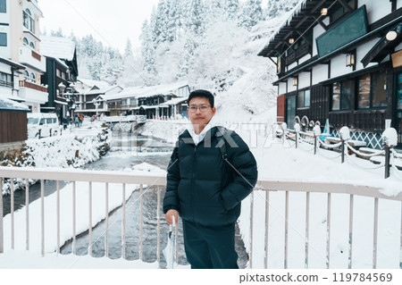 man tourist Visiting Ginzan Onsen in Yamagata, happy Traveler sightseeing Japanese Onsen village with Snow in winter season. landmark and popular for attraction in Japan. Travel and Vacation concept 119784569