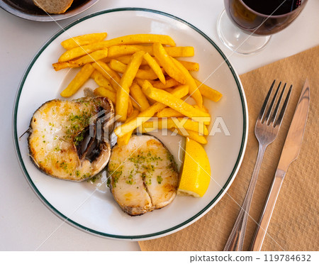 Grilled hake served with potatoes and lemon 119784632
