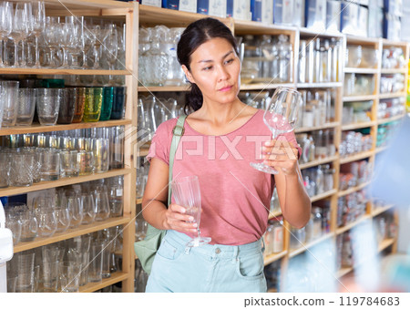 Woman choosing new glasses in dinnerware store Woman choosing new glasses in dinnerware store 119784683