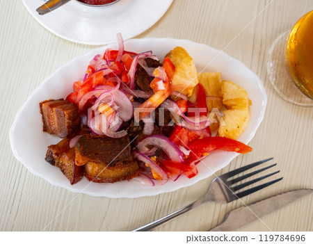 Fried pork is laid out on plate, with fried cassava and salad - Latin American tapita dish. Fried pork is laid out on plate, with fried cassava and salad - Latin American tapita dish. 119784696