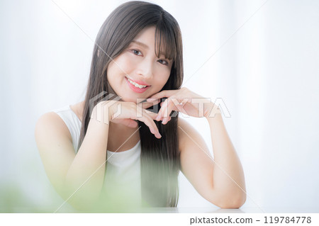A young cute woman looking at the camera in a cute pose with her hand on her chin and her chin resting on her hand A young cute woman looking at the camera in a cute pose with her hand on her chin and her chin resting on her hand 119784778