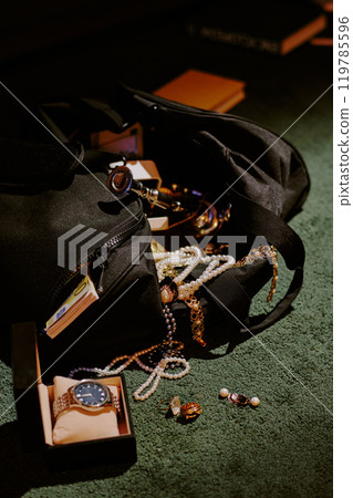 Vertical shot of fabric bag with stolen jewelry and golden watch on floor Vertical shot of fabric bag with stolen jewelry and golden watch on floor 119785596