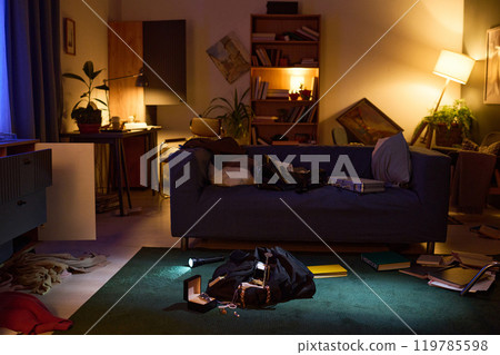 Mess on floor and broken furniture in dimly lit living room after break-in 119785598