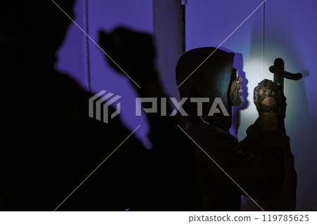 Back shot of unrecognizable thief with flashlight illuminating doors lock while his African American partner picking lock Back shot of unrecognizable thief with flashlight illuminating doors lock while his African American partner picking lock 119785625