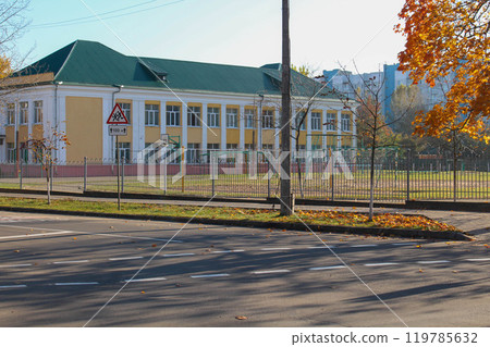 A two-story school building in the fall. Sports ground on the school grounds.  119785632