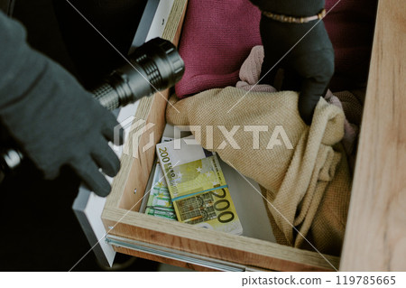 High angle shot of unrecognizable thief going through dresser with clothes and pack of money 119785665