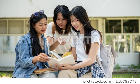 A group of Asian female college students is discussing topics from a book in their college park. 119785775