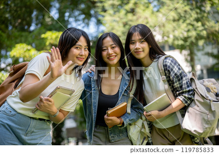 Portrait of charming and friendly Asian female college students waving and smiling at the camera. 119785833