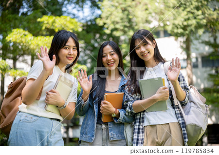 Portrait of charming and friendly Asian female college students waving and smiling at the camera. 119785834