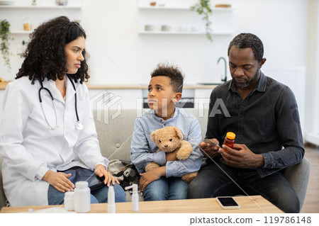Doctor advises father and son about medication at home visit 119786148