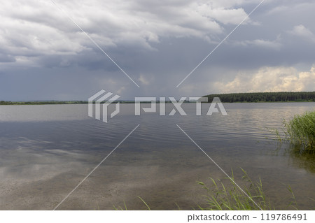 lake and trees on the shore before a storm lake and trees on the shore before a storm 119786491