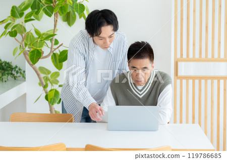 Senior man learning how to use a computer in the living room 119786685