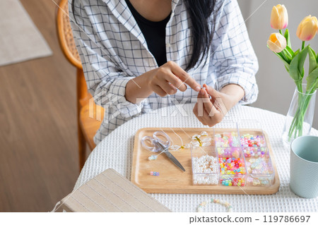 Young girl making handmade bracelets with fun and cheerfulness 119786697