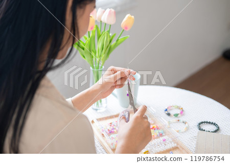 Young girl making handmade bracelets with fun and cheerfulness Young girl making handmade bracelets with fun and cheerfulness 119786754