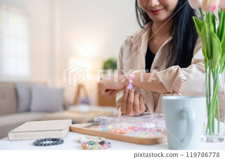 Young girl making handmade bracelets with fun and cheerfulness 119786778