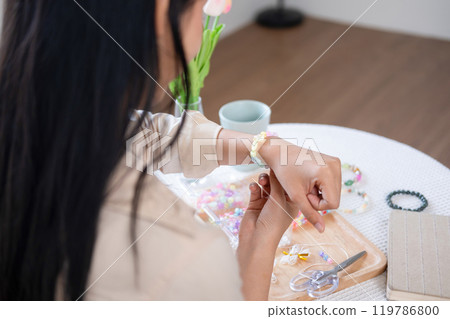 Young girl making handmade bracelets with fun and cheerfulness 119786800