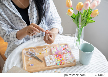 Young girl making handmade bracelets with fun and cheerfulness Young girl making handmade bracelets with fun and cheerfulness 119786865