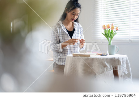 Young girl making handmade bracelets with fun and cheerfulness 119786904