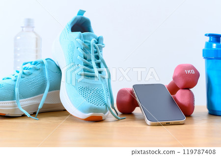 Tools to start exercising: Light blue sneakers, water, dumbbells and smartphone background material 119787408