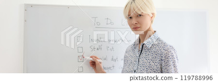 Lady worker marks point of business plan on board in office Lady worker marks point of business plan on board in office 119788996