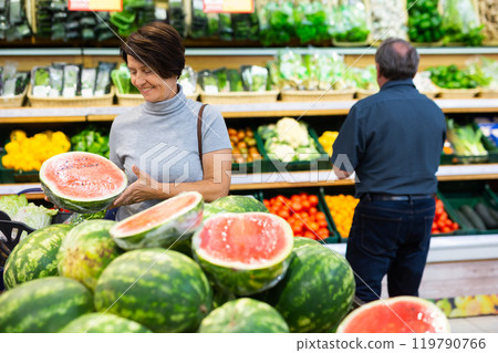 Elderly woman chooses watermelon in fruit and vegetable section 119790766