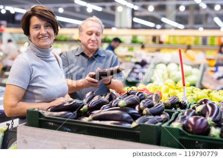 Elderly woman and man choose eggplants in vegetable and fruit department Elderly woman and man choose eggplants in vegetable and fruit department 119790779