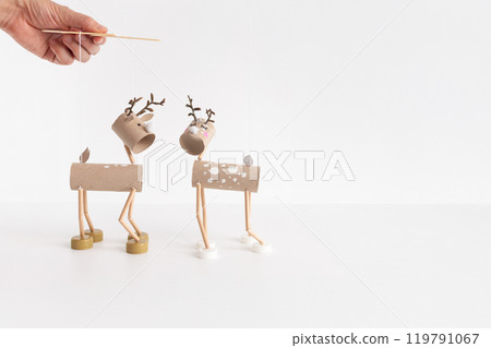 DIY toilet paper roll craft for kids featuring homemade reindeer marionette toy from recycled materials. Easy New Year craft and children's activity idea. Creative holiday project 119791067