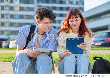 Teenage college students guy and girl talking, sitting outdoor Teenage college students guy and girl talking, sitting outdoor 119791658