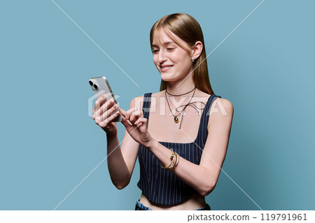 Young beautiful woman using smartphone on blue studio background Young beautiful woman using smartphone on blue studio background 119791961