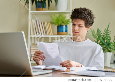 Serious young guy reading letter, paper document 119792099