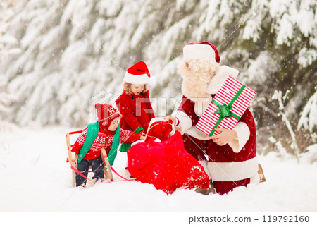 Kids and Santa with Christmas gifts in snow forest 119792160