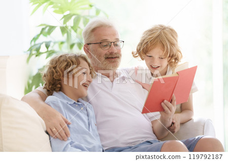 Grandfather and kids read book at home. 119792187
