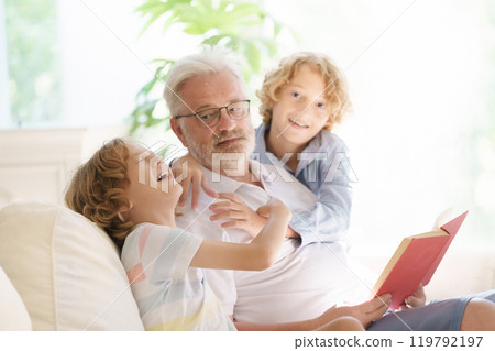Grandfather and kids read book at home. 119792197
