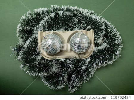 Christmas disco balls with green garland in a paper cup holder 119792424