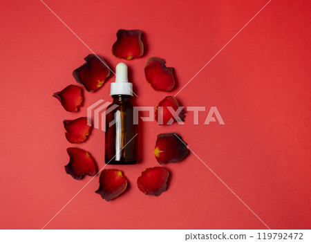 cosmetic serum bottle with red rose petals on red background cosmetic serum bottle with red rose petals on red background 119792472