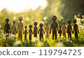 Wooden figurines standing together in a sunlit meadow, showcasing unity and diversity 119794725