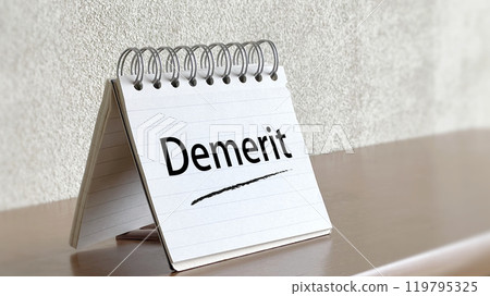 Notepad on a table with Demerit text 119795325