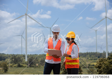 Team engineer wearing safety uniform holding laptop discussed plan about renewable energy at station energy power wind. technology protect environment reduce global warming problems. 119796068