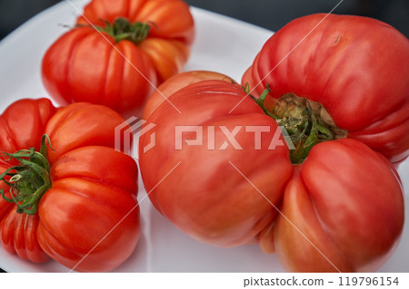 Red tomatoes on the white plate, black table background Red tomatoes on the white plate, black table background 119796154
