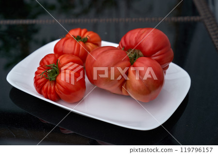 Red tomatoes on the white plate, black table background Red tomatoes on the white plate, black table background 119796157