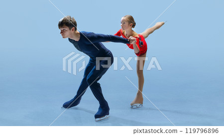 Figure skating duo showing off their athleticism and grace as they perform complex lift on ice against cold blue background, beautifully demonstrated elegance. 119796896