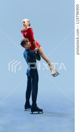 Professional figure skating couple demonstrating elegant lift during their performance against cold blue background. 119796900