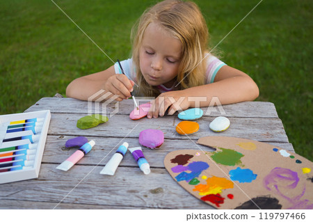 Child craft activities, girl paints heart on stones. Preschooler art work. Mother's day handmade present. Child craft activities, girl paints heart on stones. Preschooler art work. Mother's day handmade present. 119797466