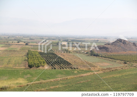 Stunning Aerial View of Lush Vineyards and Orchards with Majestic Mountains in the Background Stunning Aerial View of Lush Vineyards and Orchards with Majestic Mountains in the Background 119797709