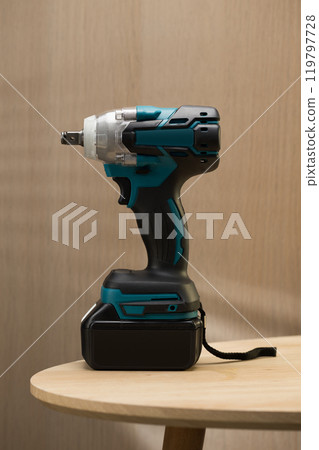 Cordless electric drill and screwdriver on a wooden table. 119797728