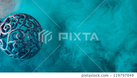 Christmas magic. Cyan smoke background. Shiny intricate Xmas bauble blue mist cloud spreading on red shimmering glitter texture surface. 119797849