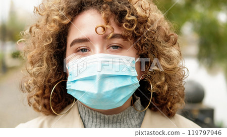 Quarantine face. Pandemic life. Air pollution. Infection prevention. Closeup portrait of woman with sad hopeful eyes in protective medical mask. Quarantine face. Pandemic life. Air pollution. Infection prevention. Closeup portrait of woman with sad hopeful eyes in protective medical mask. 119797946