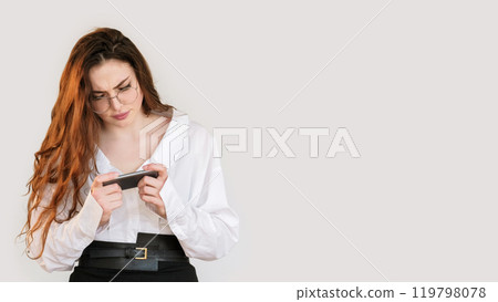 Gadget people. Mobile anxiety. Disturbed confused smart business woman in glasses watching video online on phone isolated on white copy space background. Gadget people. Mobile anxiety. Disturbed confused smart business woman in glasses watching video online on phone isolated on white copy space background. 119798078